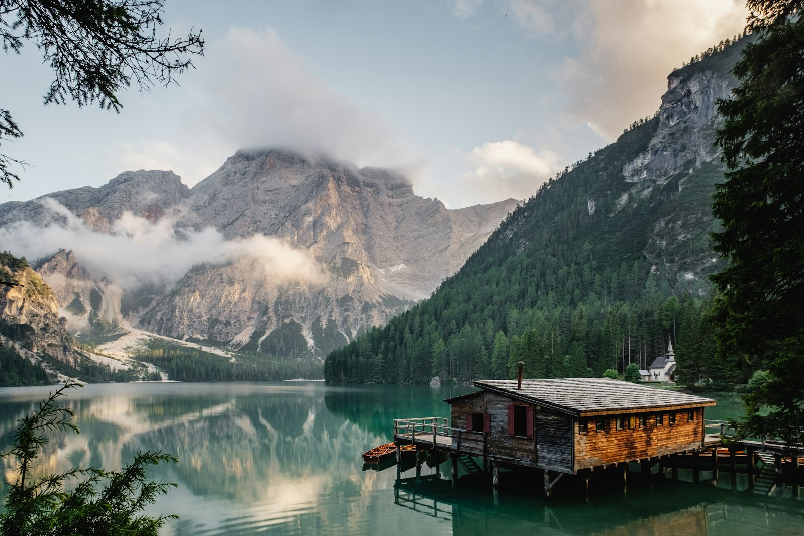 Alpiner Bergsee mit historischem Bootshaus im Vordergrund und Bergkette im Hintergrund